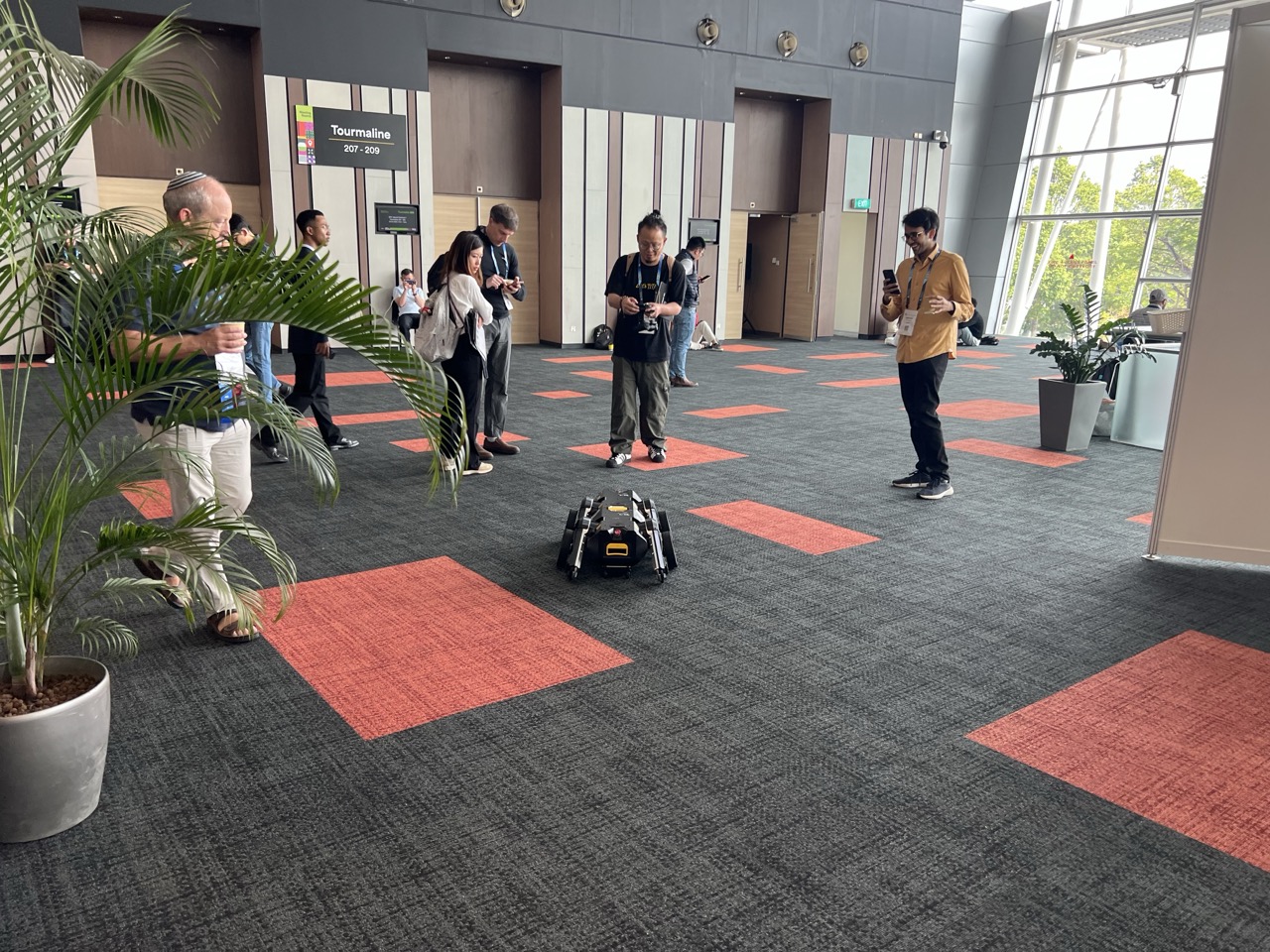 Attendees at AAAI 2026 observe a small, autonomous robot in Singapore.